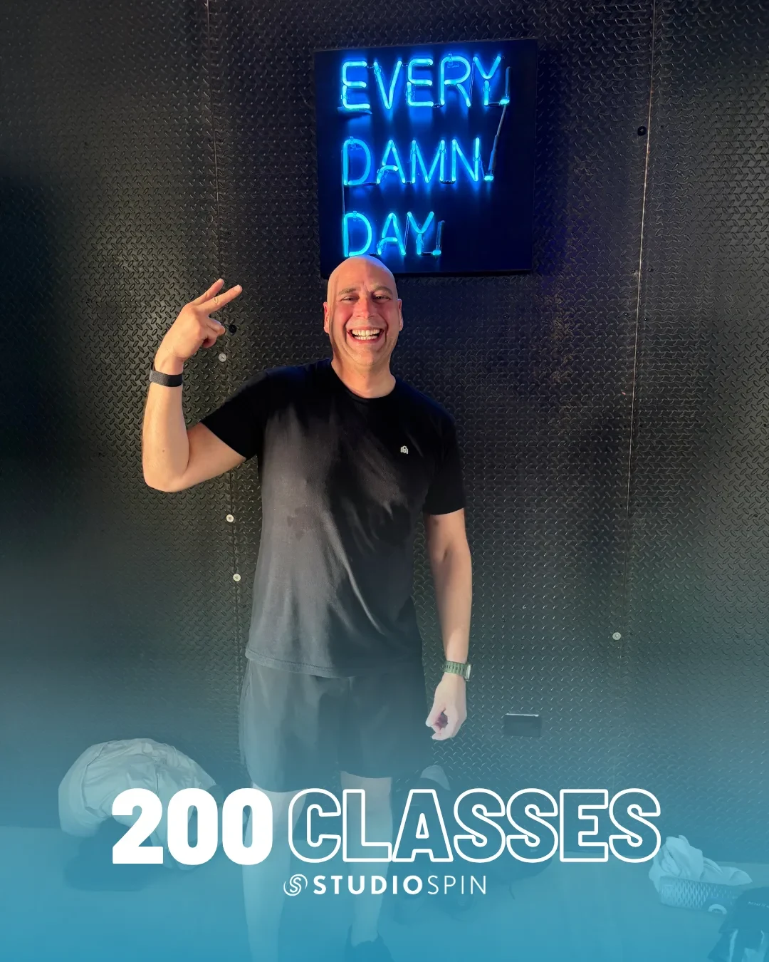 A Studio Spin member celebrating 200 classes under the Every Damn Day neon sign.