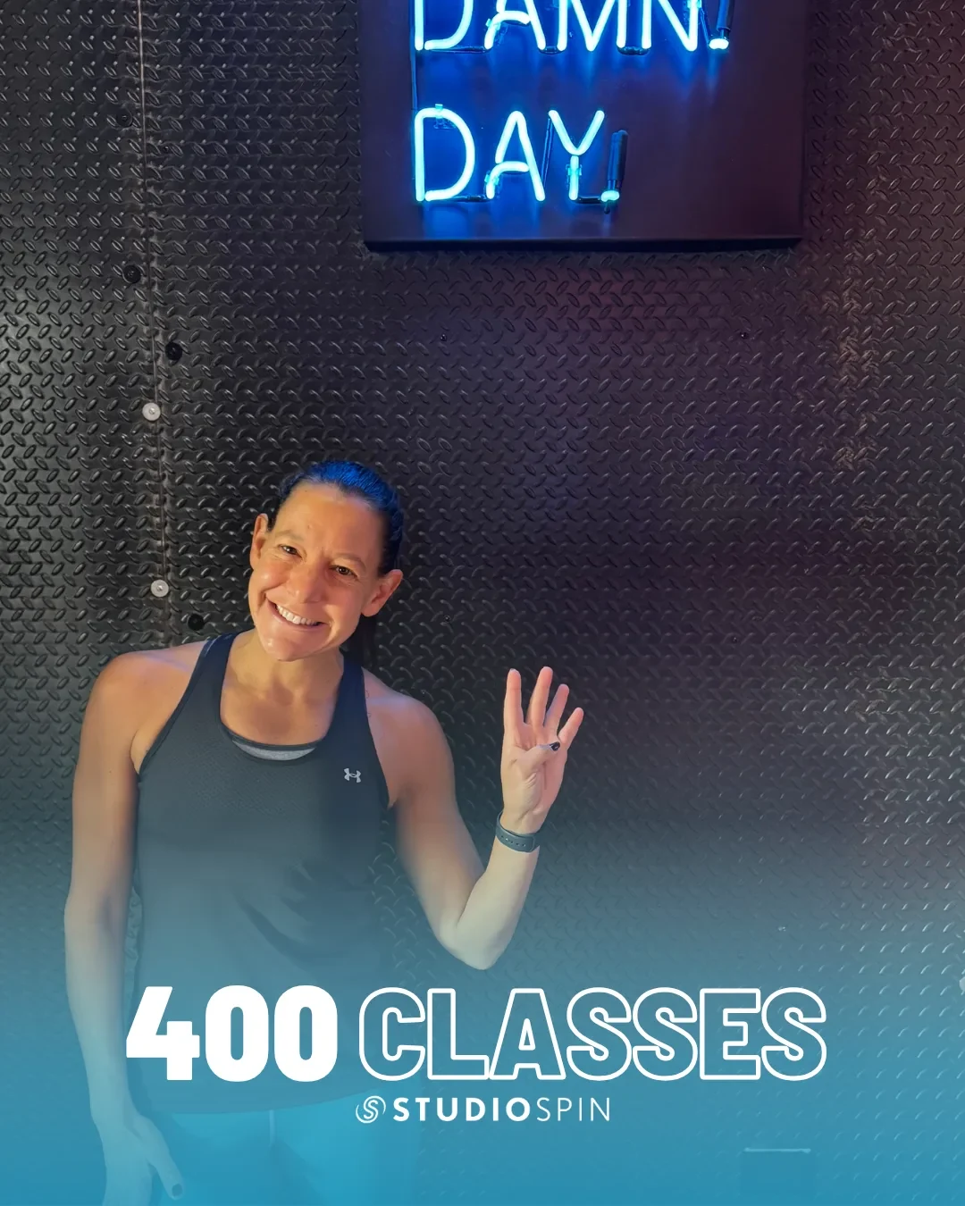 A Studio Spin member celebrating 400 classes under the Every Damn Day neon sign.
