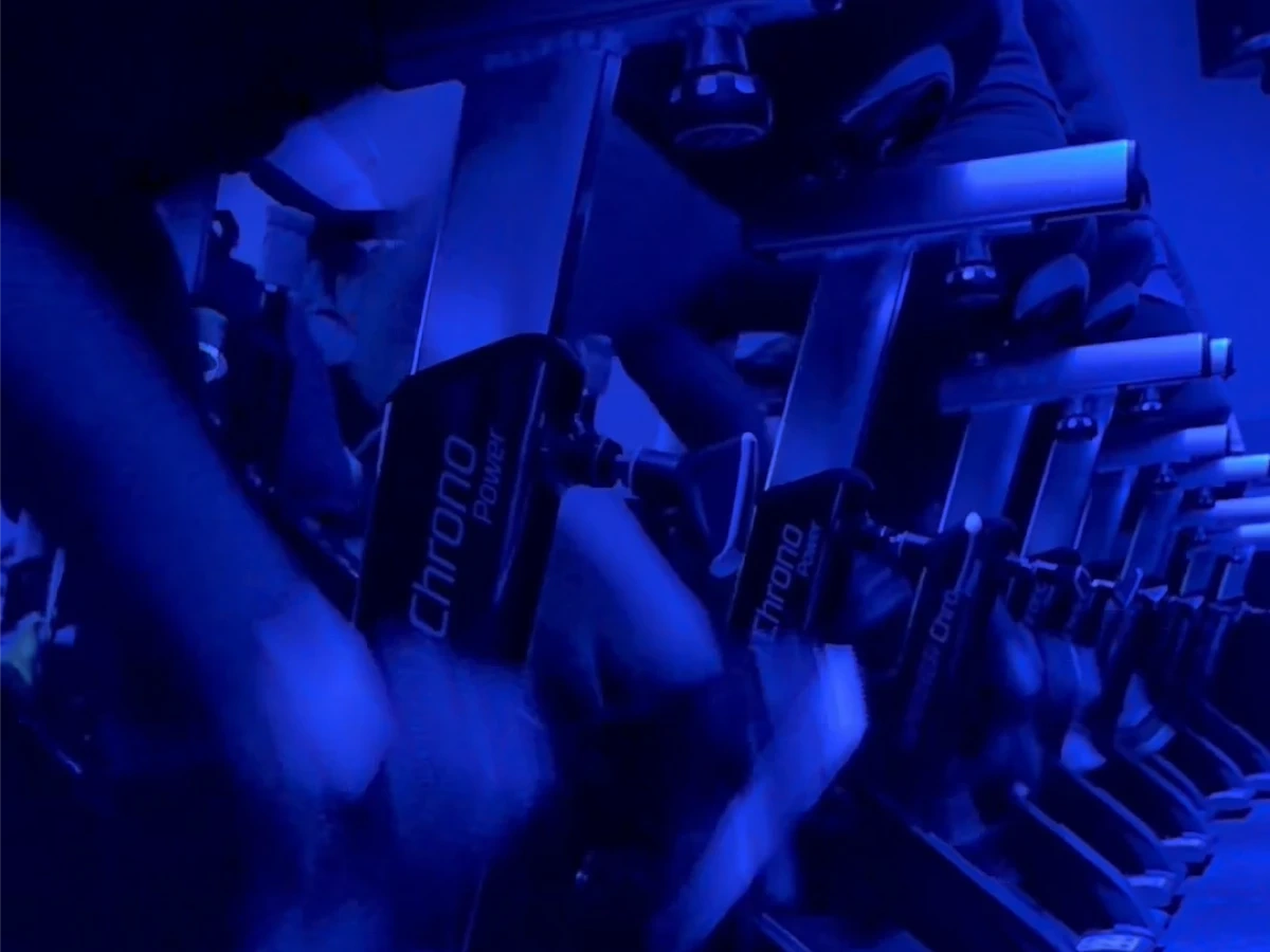 Riders pedaling a row of Chrono Power indoor cycling bikes under blue studio lights.