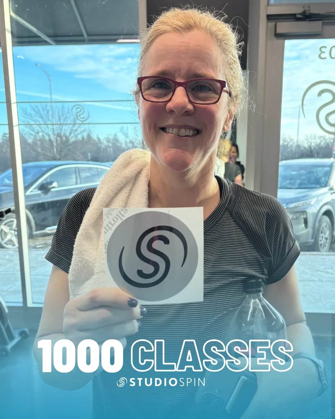 A Studio Spin member celebrating 1,000 classes under the Every Damn Day neon sign.