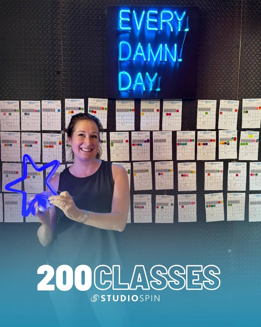 A Studio Spin member celebrating 200 classes under the Every Damn Day neon sign.