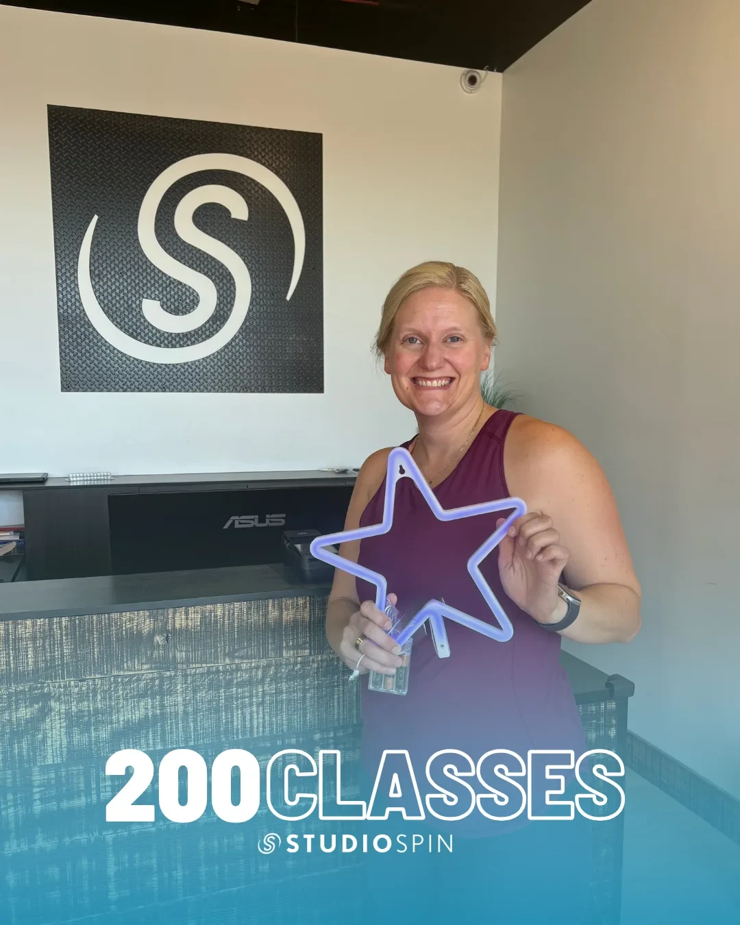 A Studio Spin member celebrating 200 classes under the Every Damn Day neon sign.