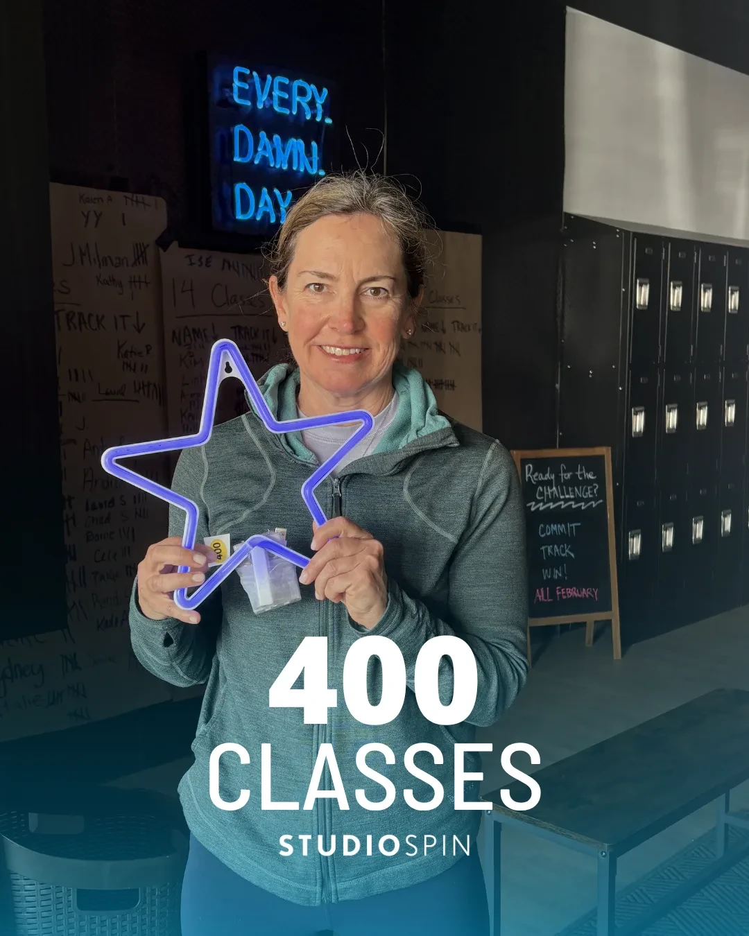A Studio Spin member celebrating 400 classes under the Every Damn Day neon sign.