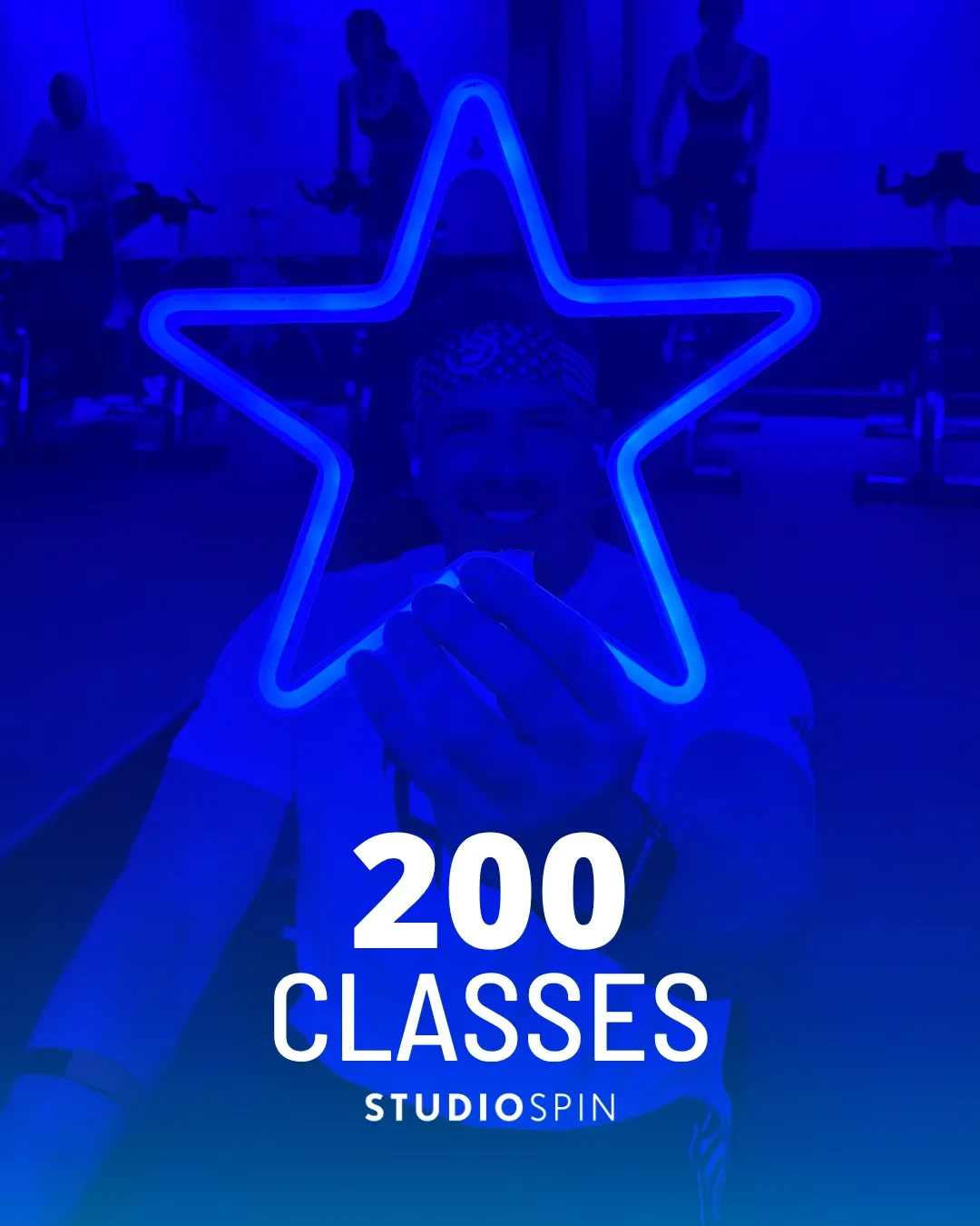 A Studio Spin member celebrating 200 classes under the Every Damn Day neon sign.