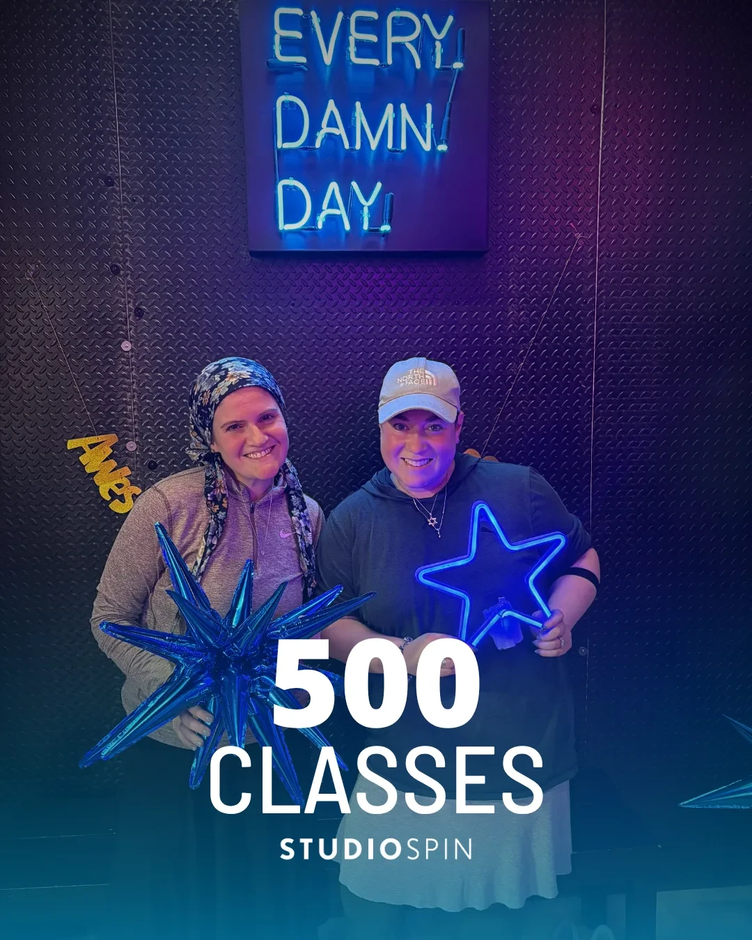 A Studio Spin member celebrating 500 classes under the Every Damn Day neon sign.