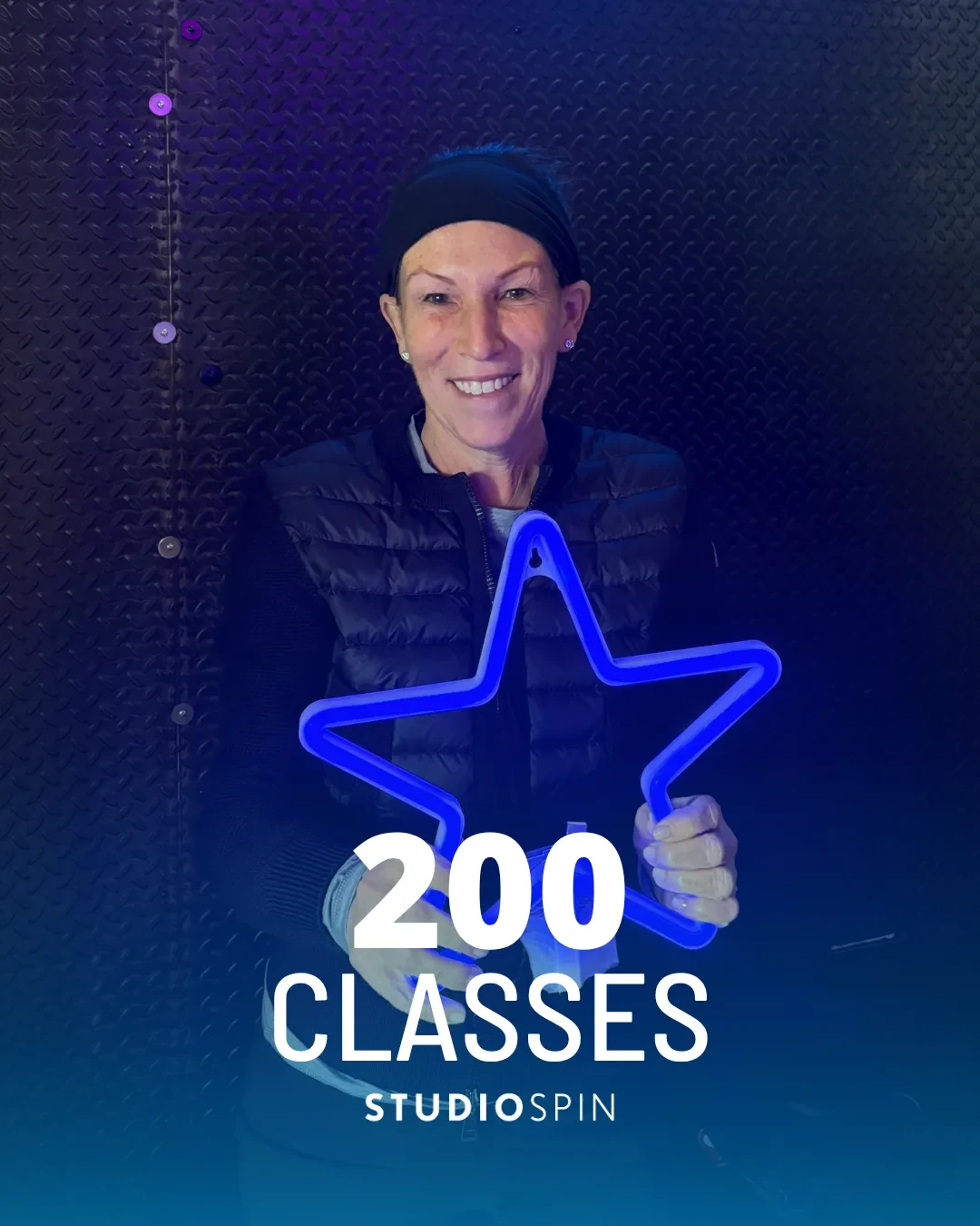 A Studio Spin member celebrating 200 classes under the Every Damn Day neon sign.