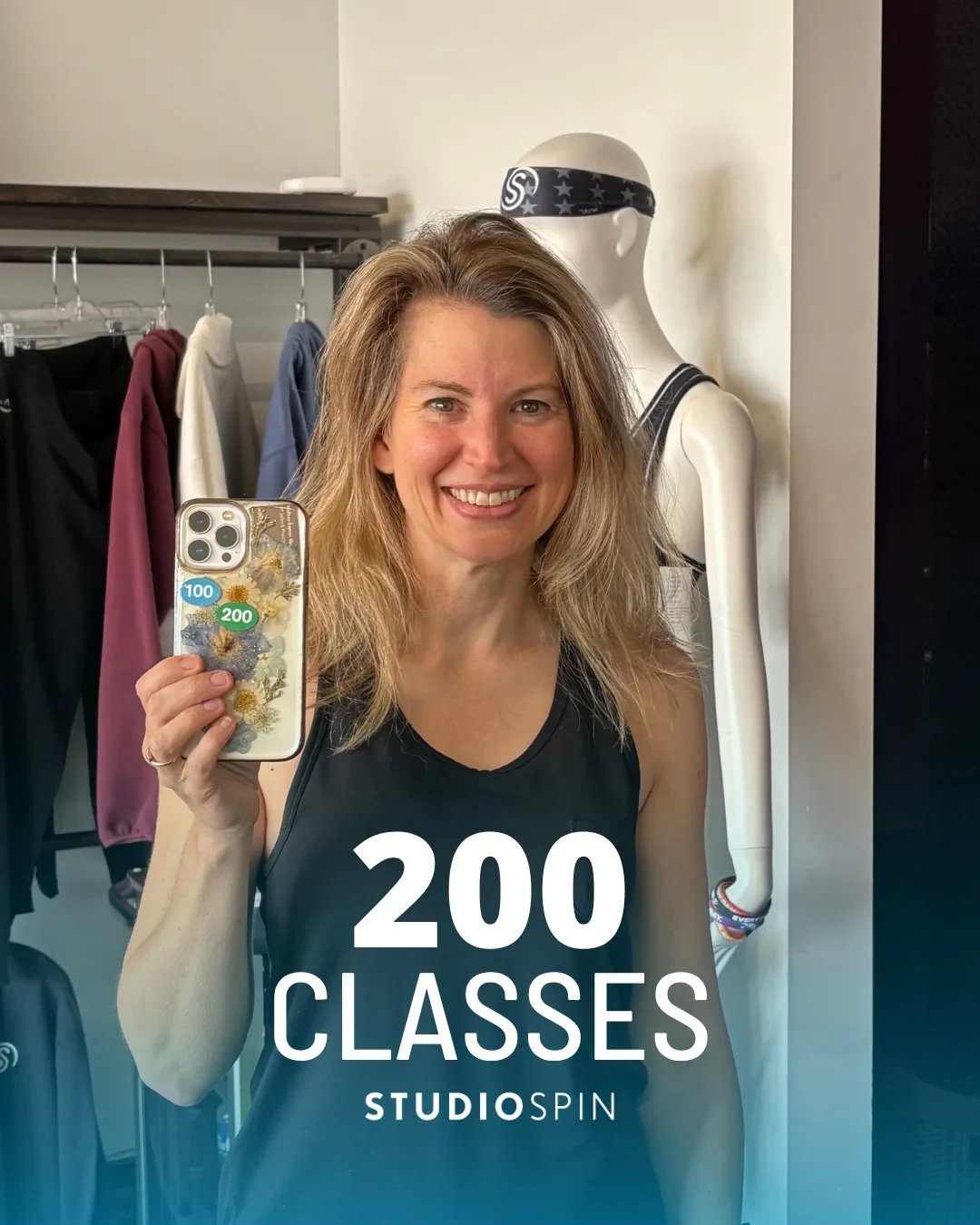 A Studio Spin member celebrating 200 classes under the Every Damn Day neon sign.