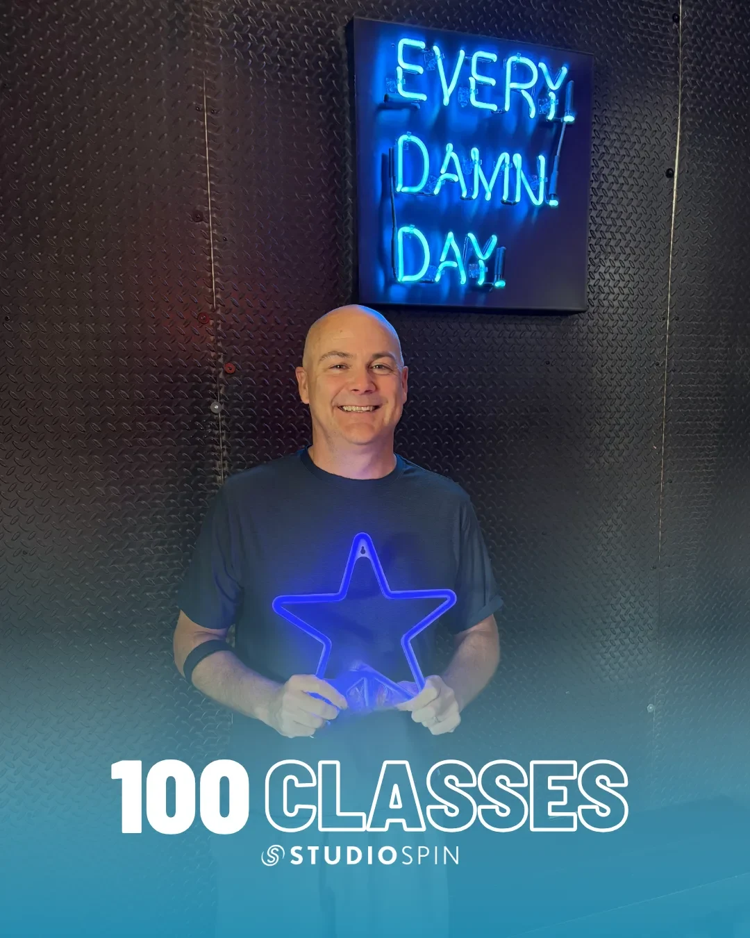 A Studio Spin member celebrating 100 classes under the Every Damn Day neon sign.