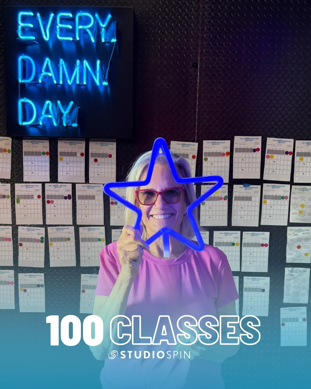 A Studio Spin member celebrating 100 classes under the Every Damn Day neon sign.