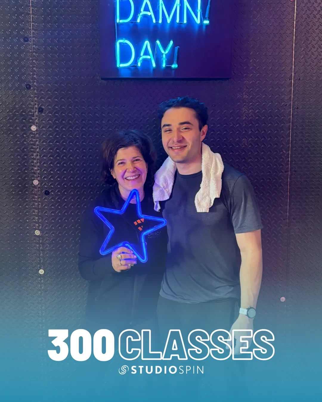 A Studio Spin member celebrating 300 classes under the Every Damn Day neon sign.