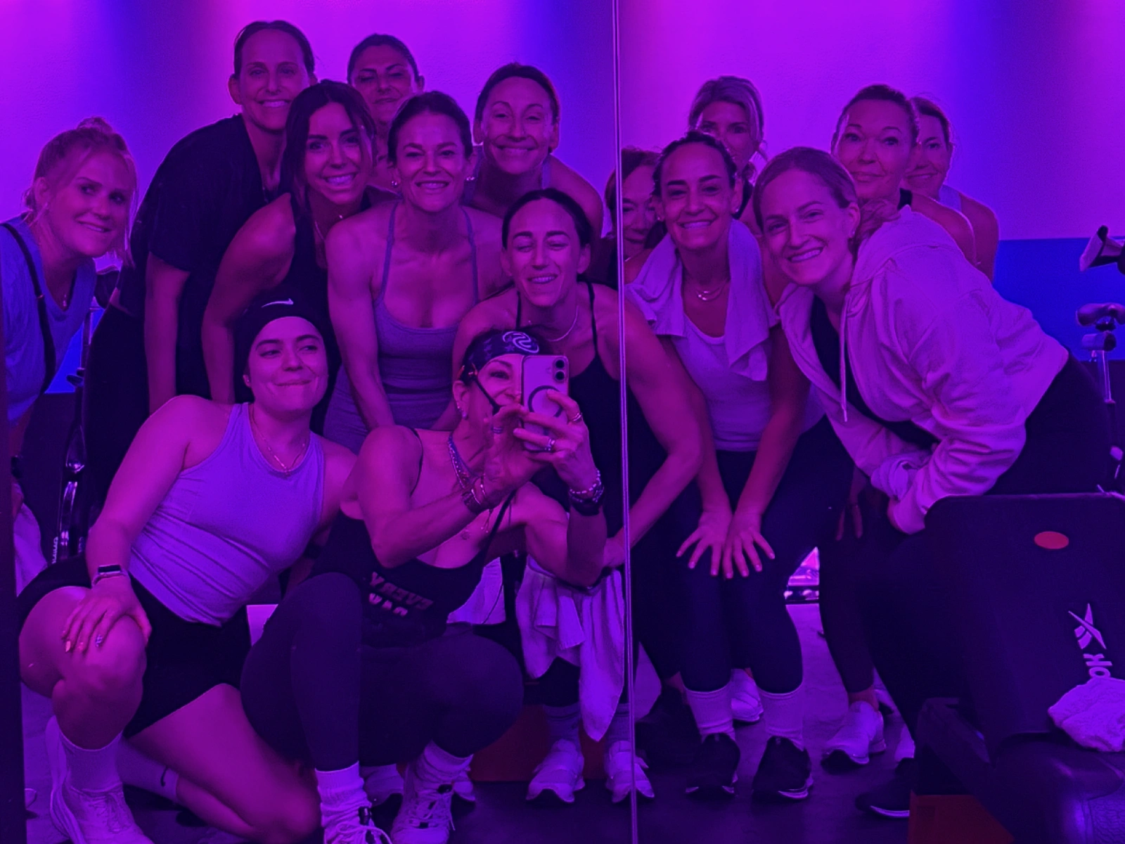 Studio Spin members smiling together after class under purple studio lights.