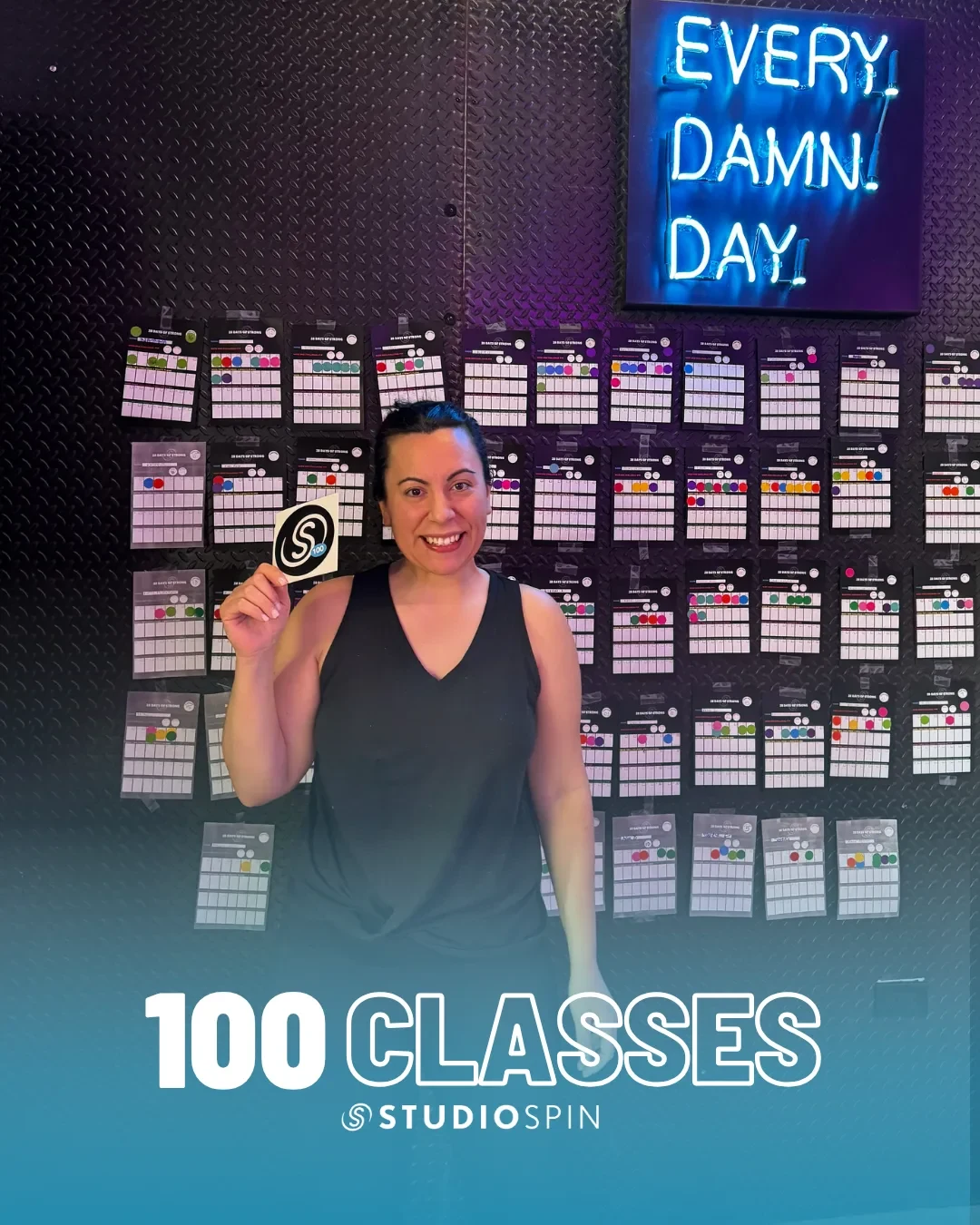 A Studio Spin member celebrating 100 classes under the Every Damn Day neon sign.