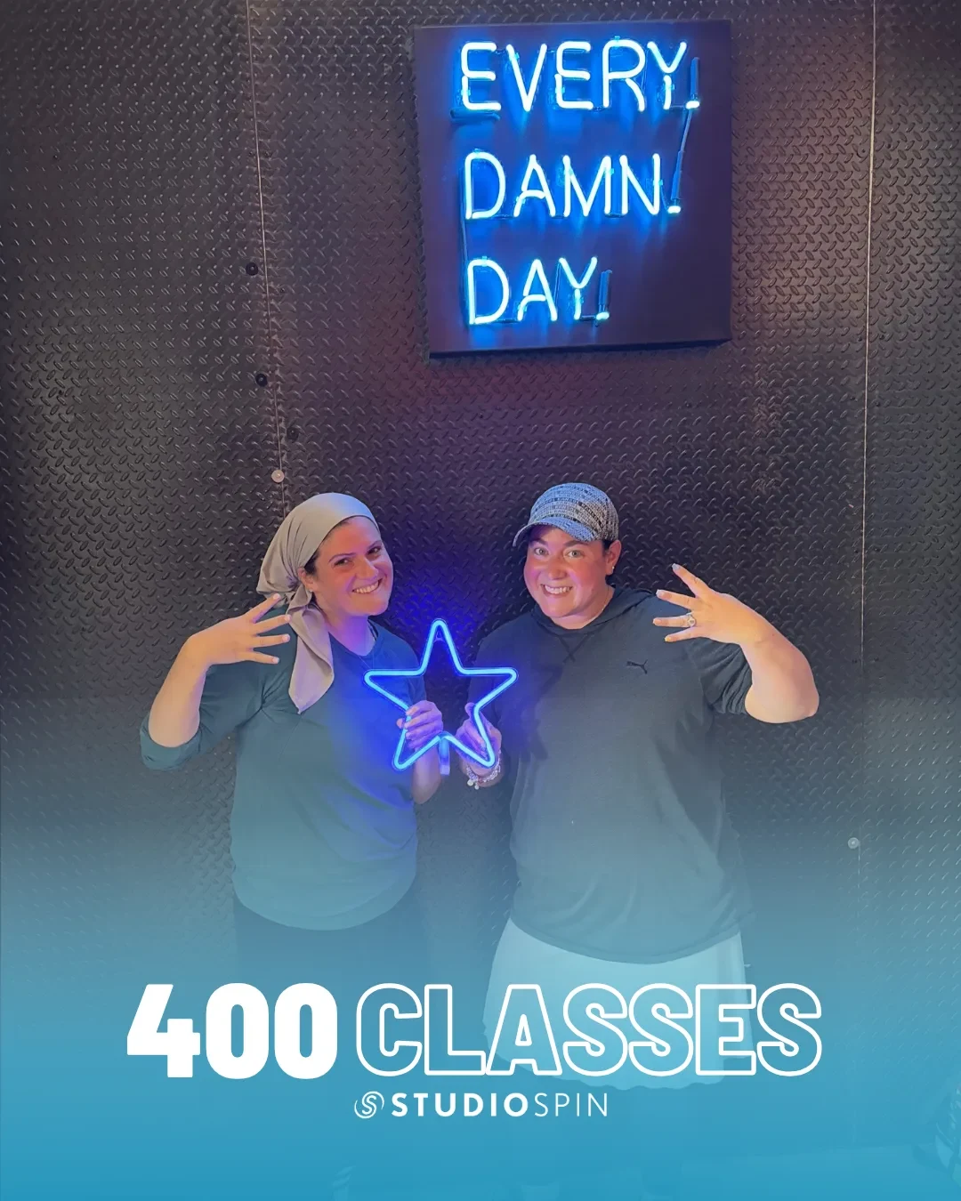 A Studio Spin member celebrating 400 classes under the Every Damn Day neon sign.