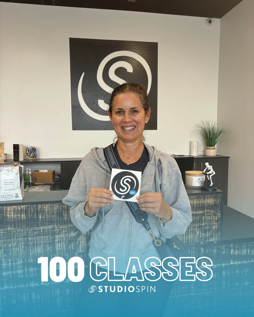 A Studio Spin member celebrating 100 classes under the Every Damn Day neon sign.