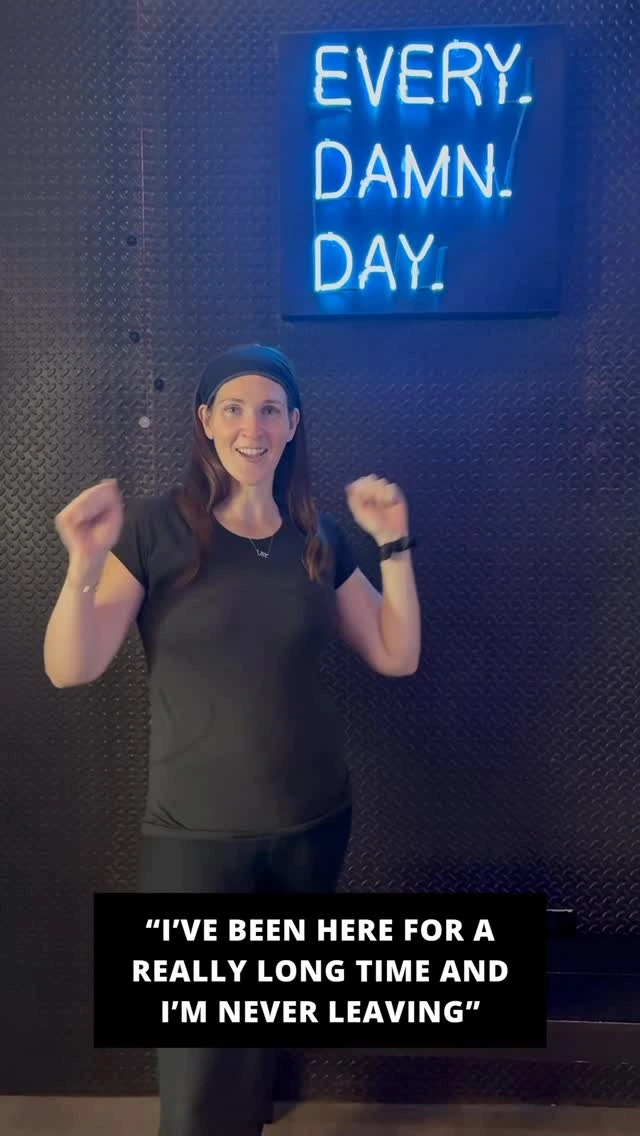A longtime Studio Spin member sharing a testimonial beneath the Every Damn Day neon sign.