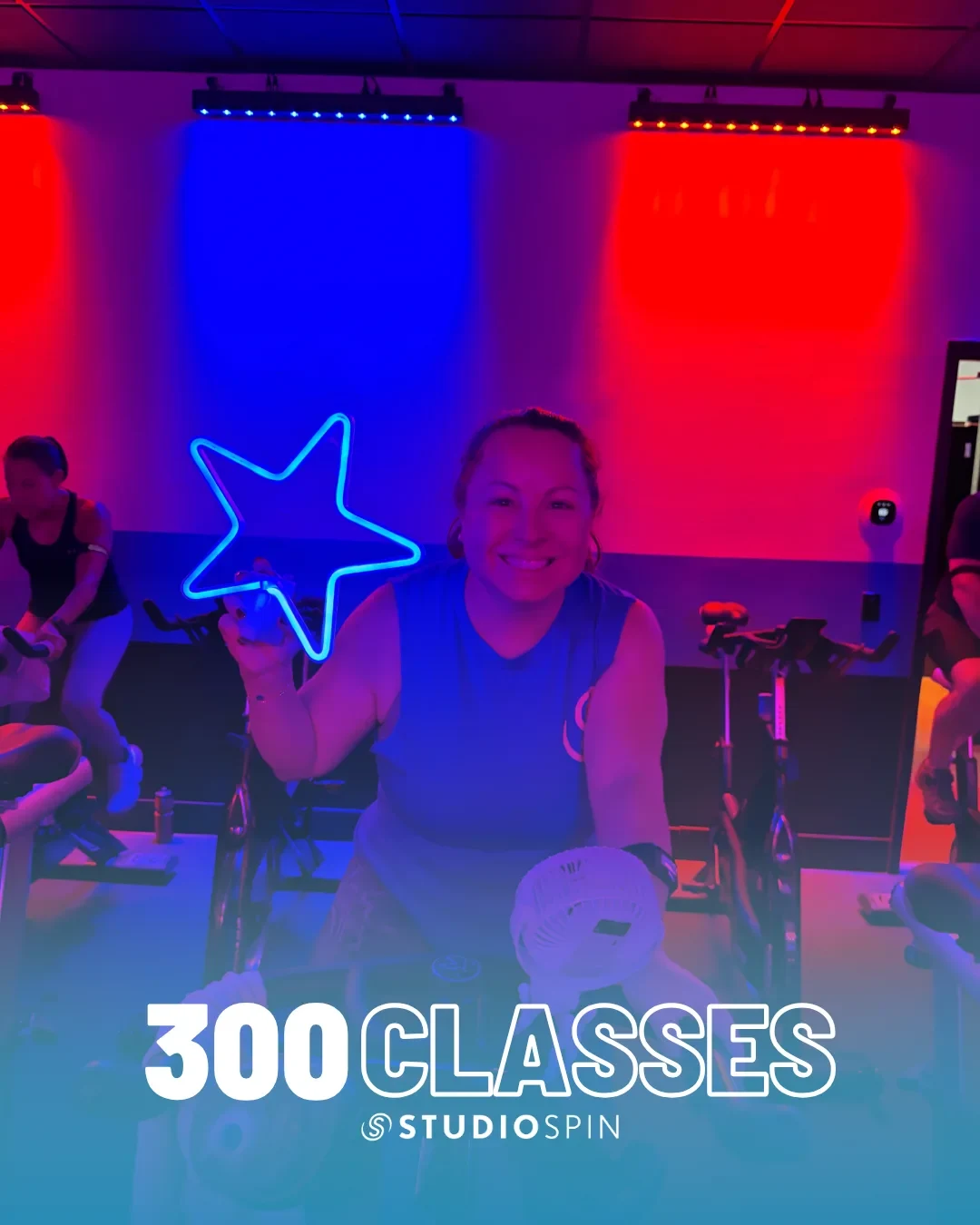 A Studio Spin member celebrating 300 classes under the Every Damn Day neon sign.