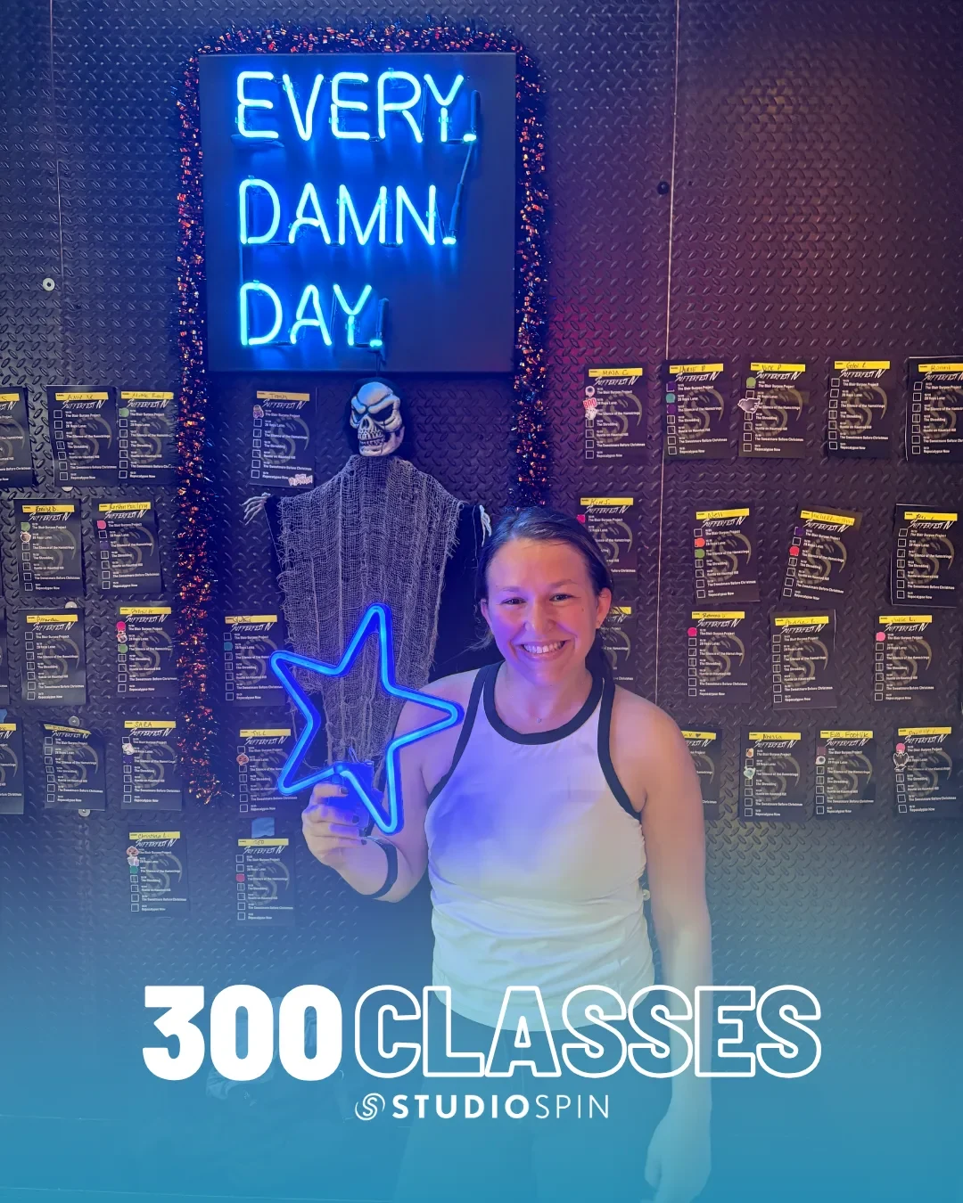 A Studio Spin member celebrating 300 classes under the Every Damn Day neon sign.