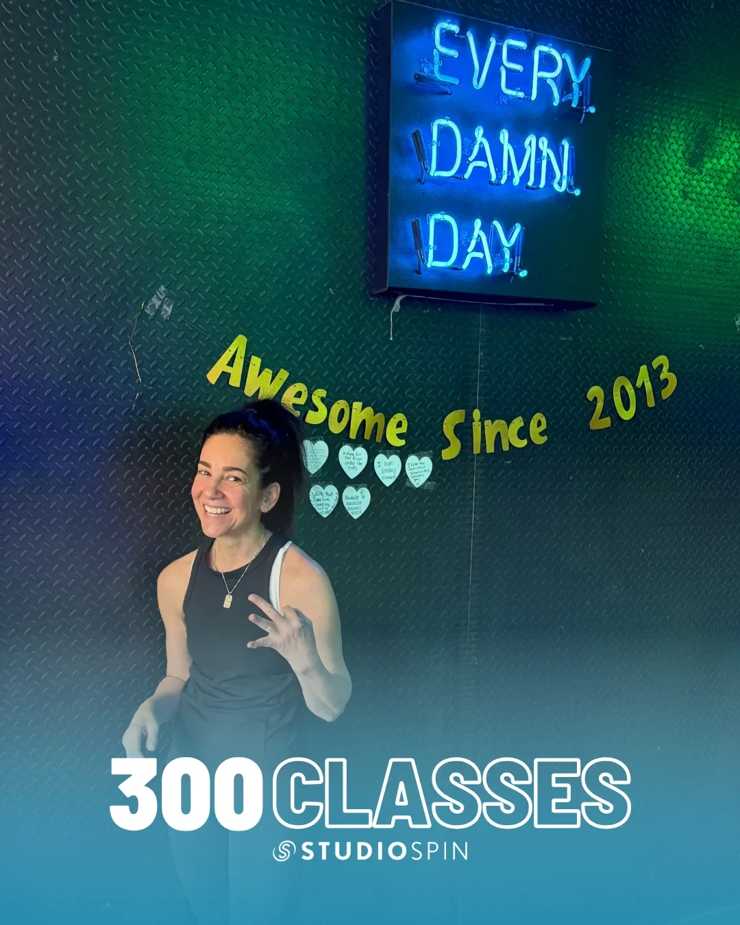 A Studio Spin member celebrating 300 classes under the Every Damn Day neon sign.