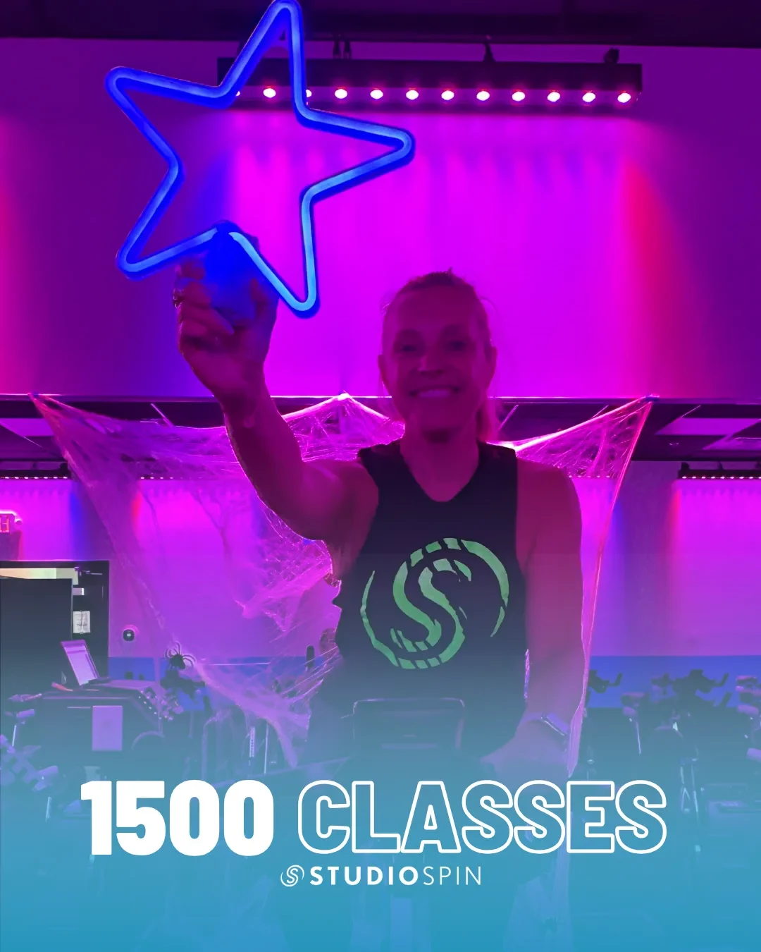 A Studio Spin member celebrating 1,500 classes under the Every Damn Day neon sign.