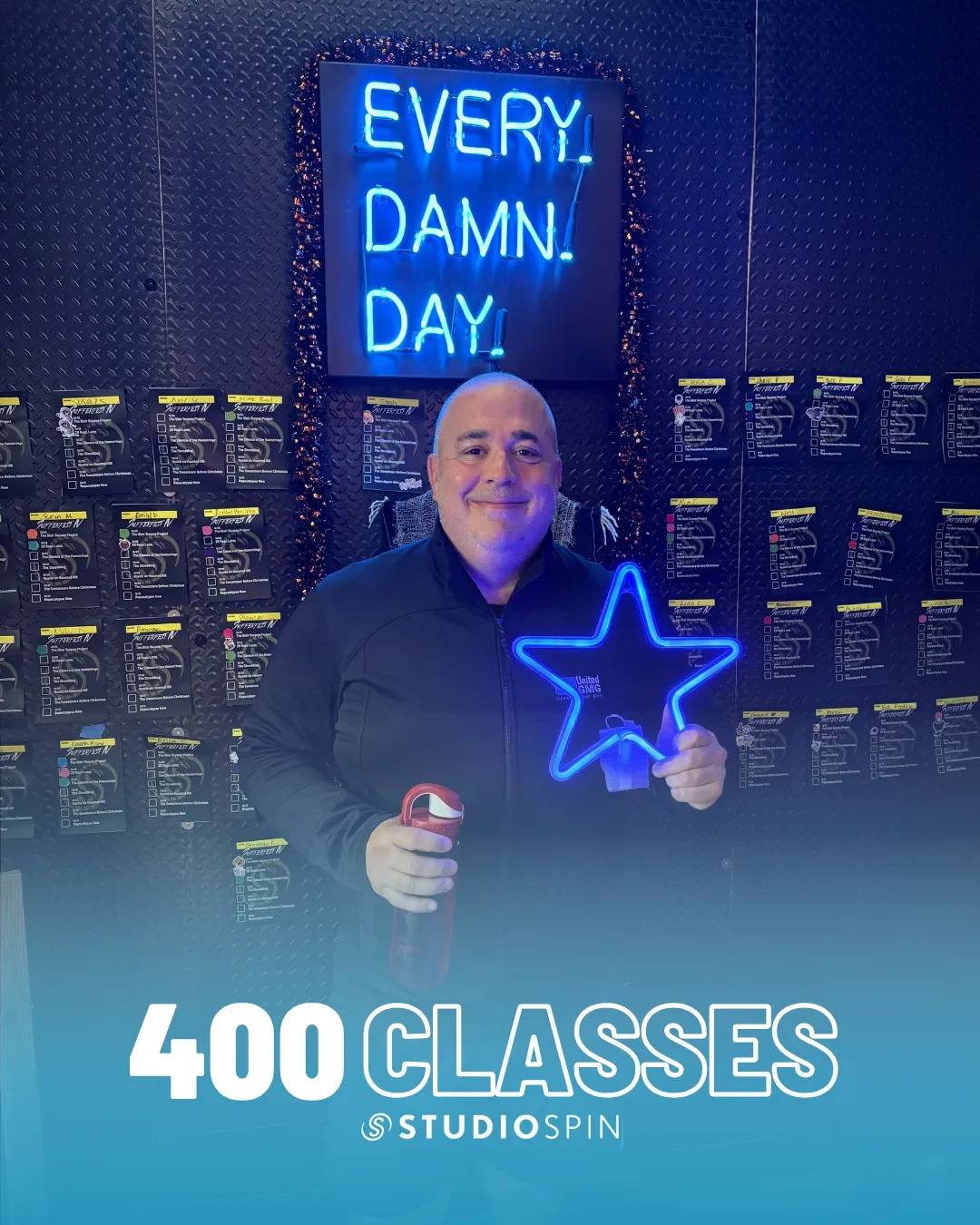 A Studio Spin member celebrating 400 classes under the Every Damn Day neon sign.