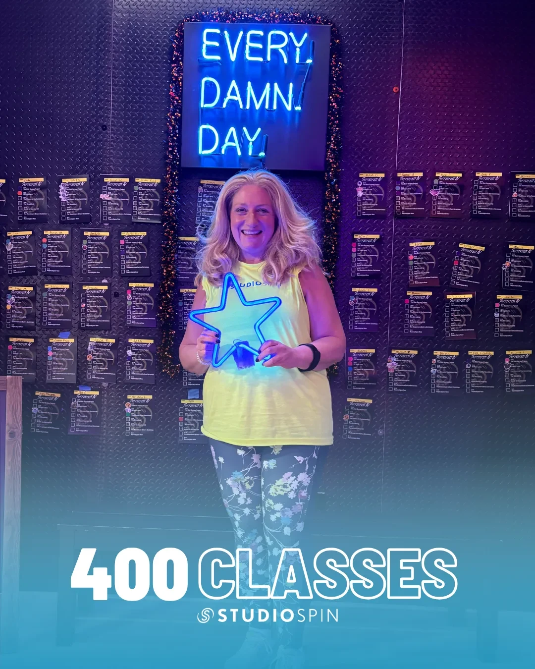 A Studio Spin member celebrating 400 classes under the Every Damn Day neon sign.