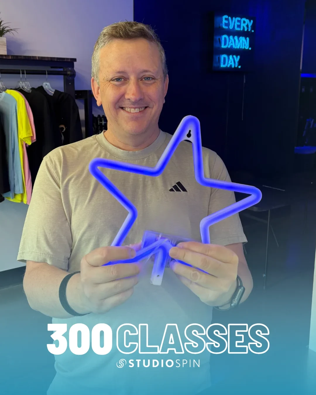 A Studio Spin member celebrating 300 classes under the Every Damn Day neon sign.