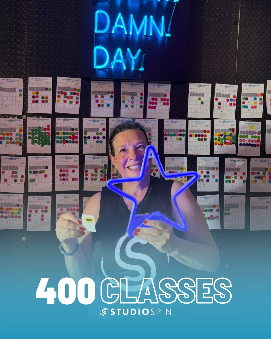 A Studio Spin member celebrating 400 classes under the Every Damn Day neon sign.