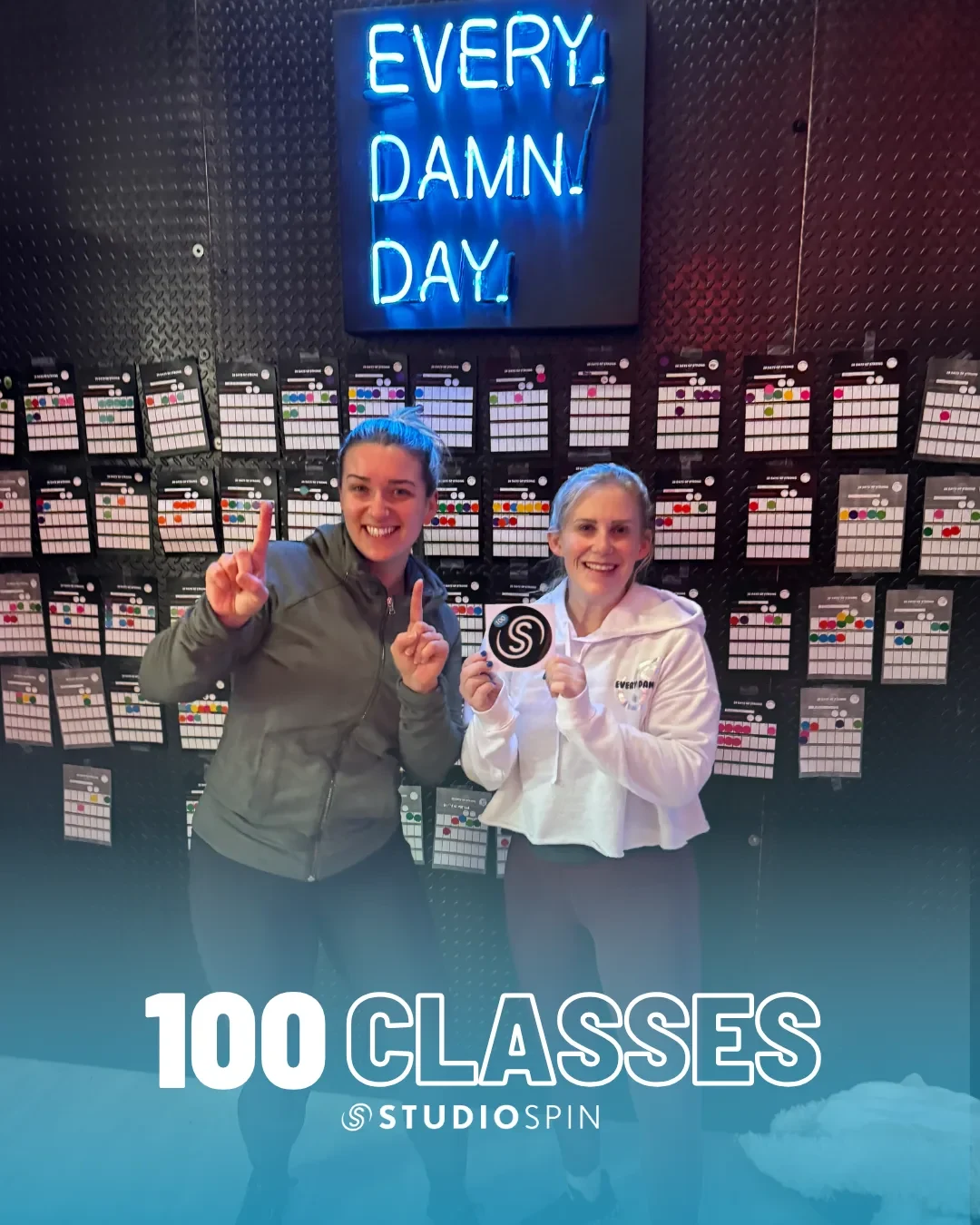 A Studio Spin member celebrating 100 classes under the Every Damn Day neon sign.