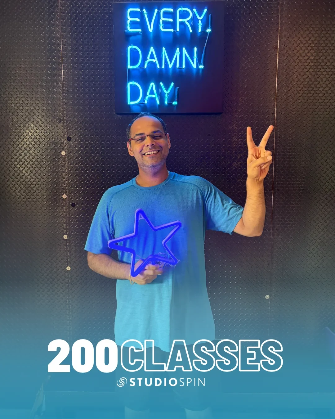 A Studio Spin member celebrating 200 classes under the Every Damn Day neon sign.