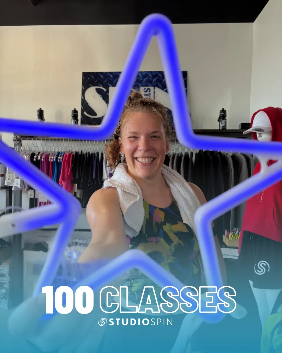 A Studio Spin member celebrating 100 classes under the Every Damn Day neon sign.