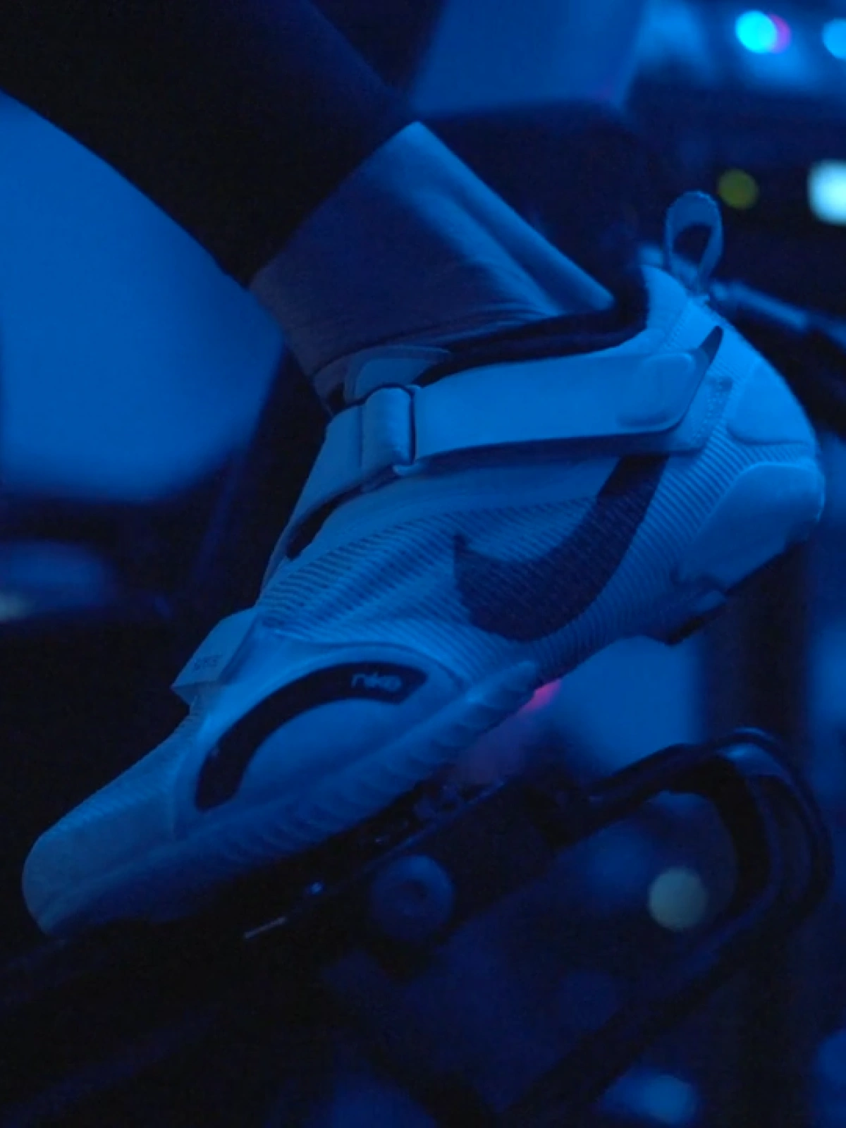 Close-up of a Studio Spin rider pedaling under blue studio lights.