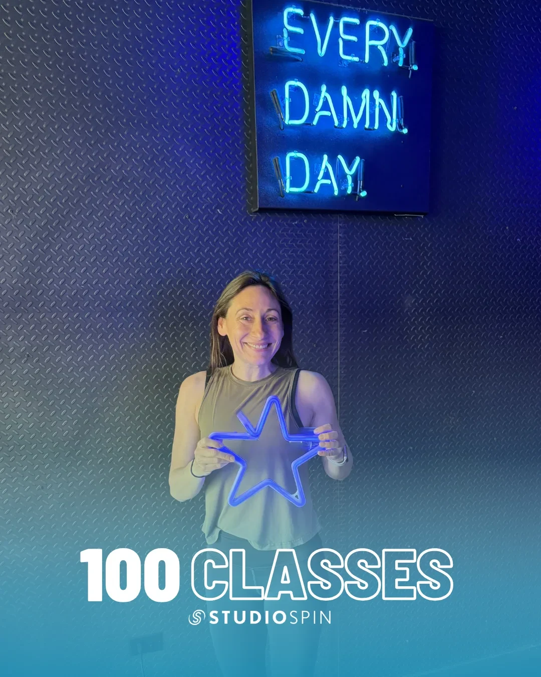 A Studio Spin member celebrating 100 classes under the Every Damn Day neon sign.