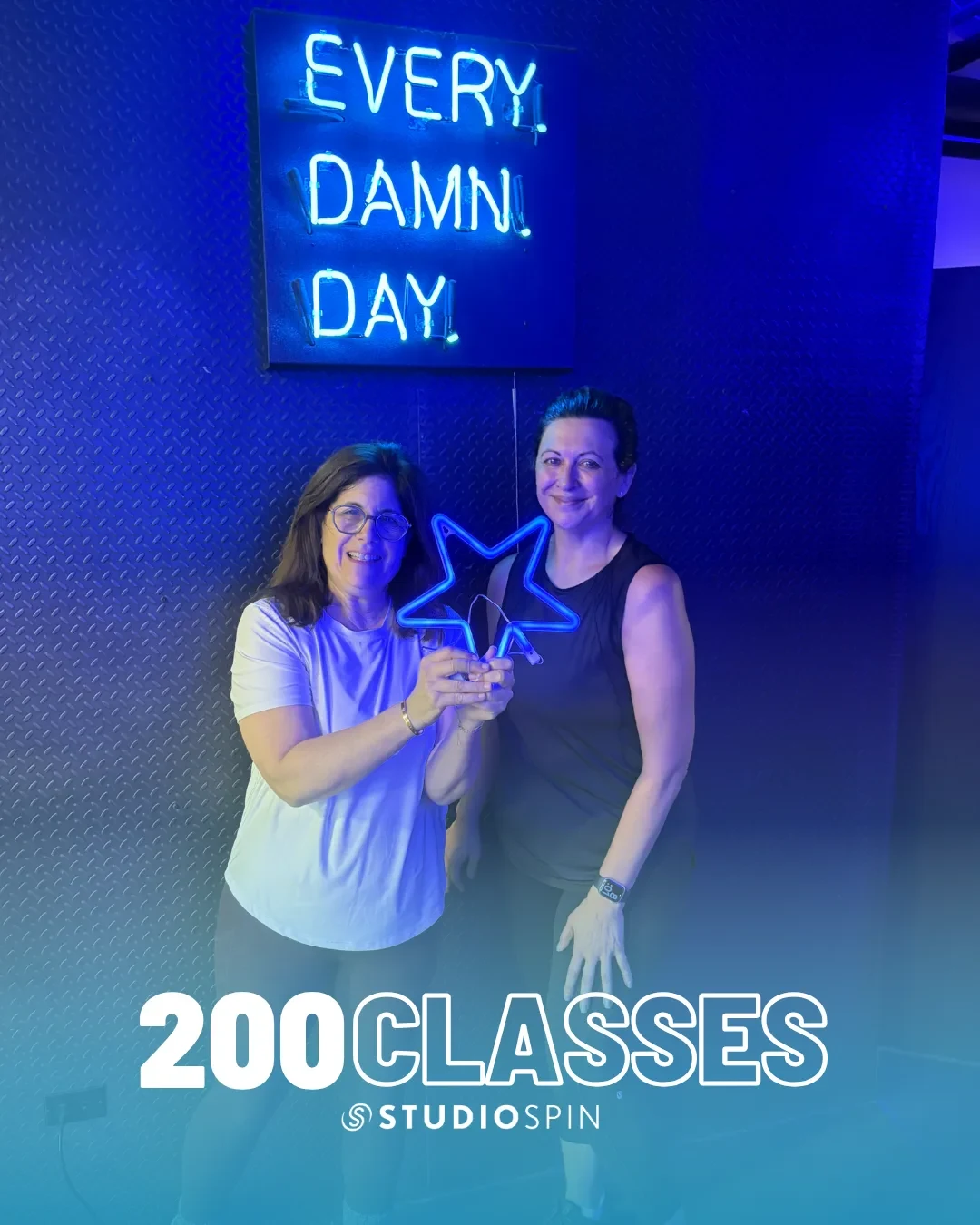A Studio Spin member celebrating 200 classes under the Every Damn Day neon sign.