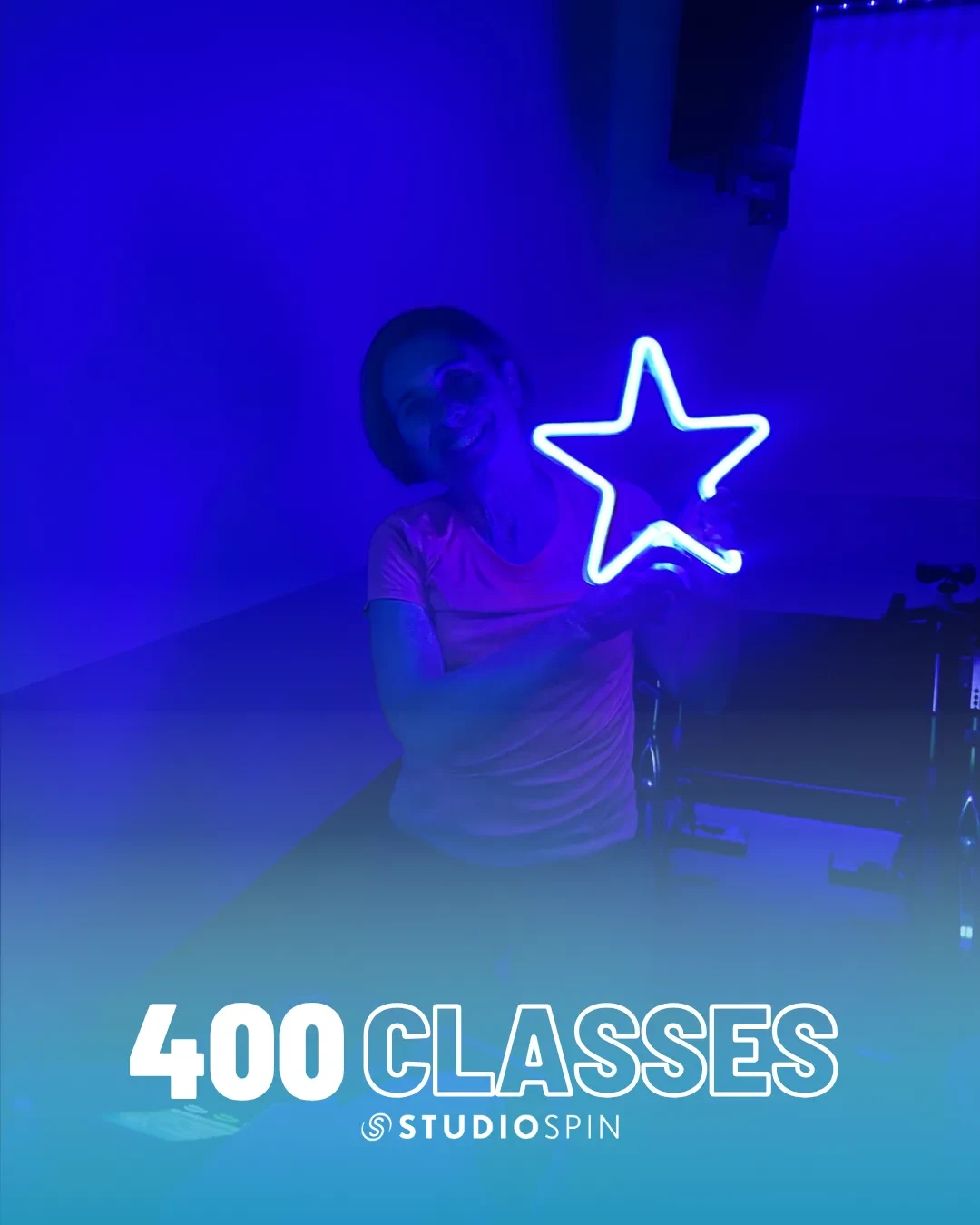 A Studio Spin member celebrating 400 classes under the Every Damn Day neon sign.