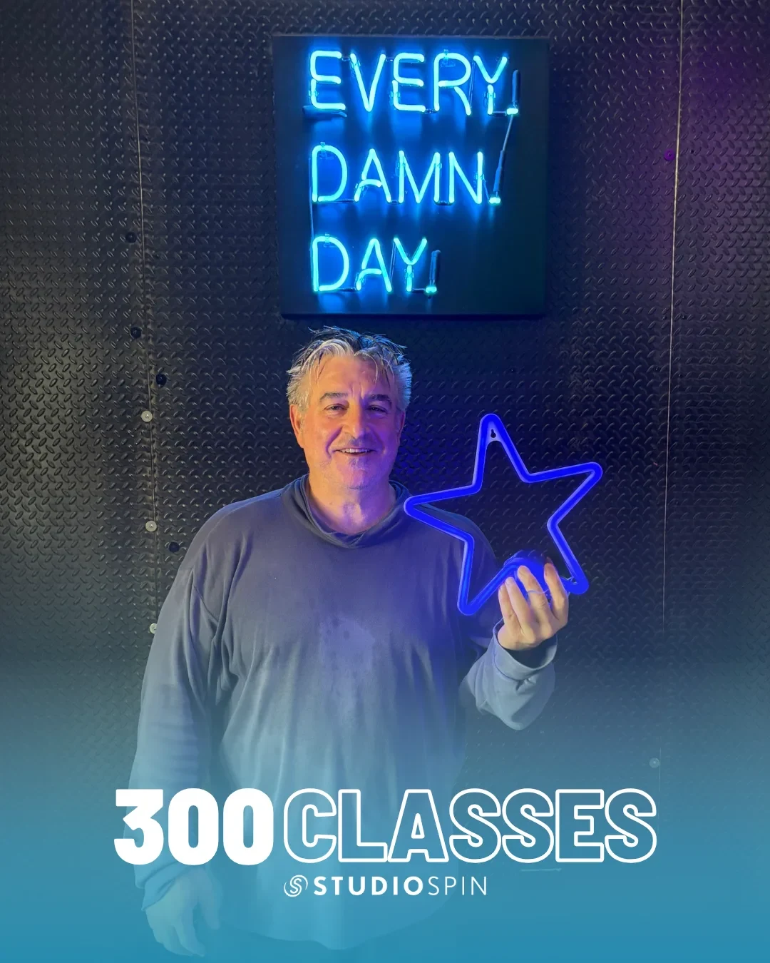 A Studio Spin member celebrating 300 classes under the Every Damn Day neon sign.