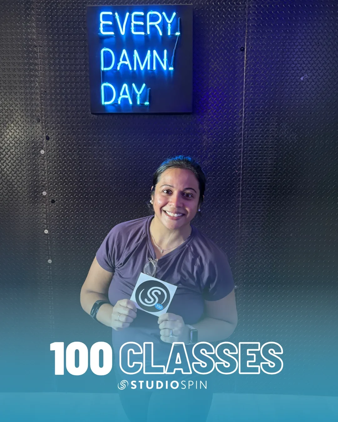 A Studio Spin member celebrating 100 classes under the Every Damn Day neon sign.