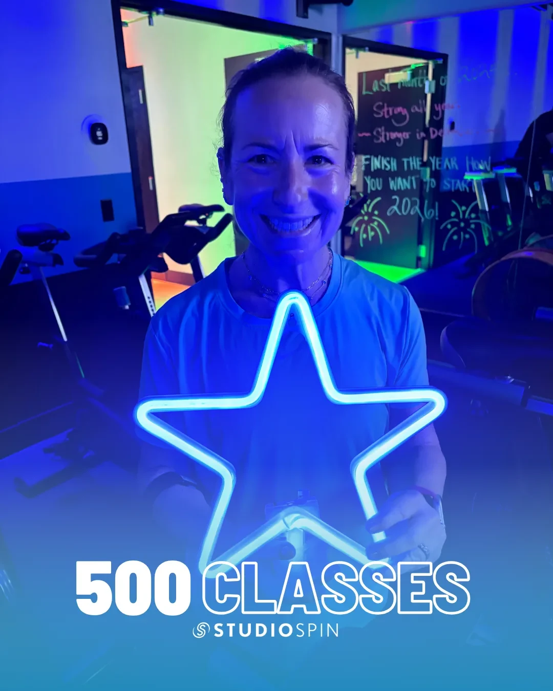 A Studio Spin member celebrating 500 classes under the Every Damn Day neon sign.