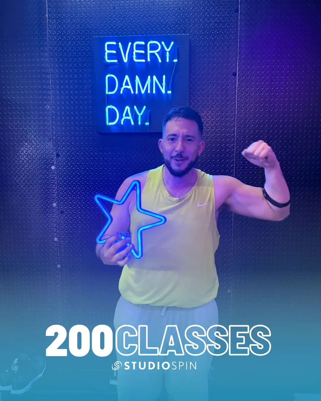 A Studio Spin member celebrating 200 classes under the Every Damn Day neon sign.