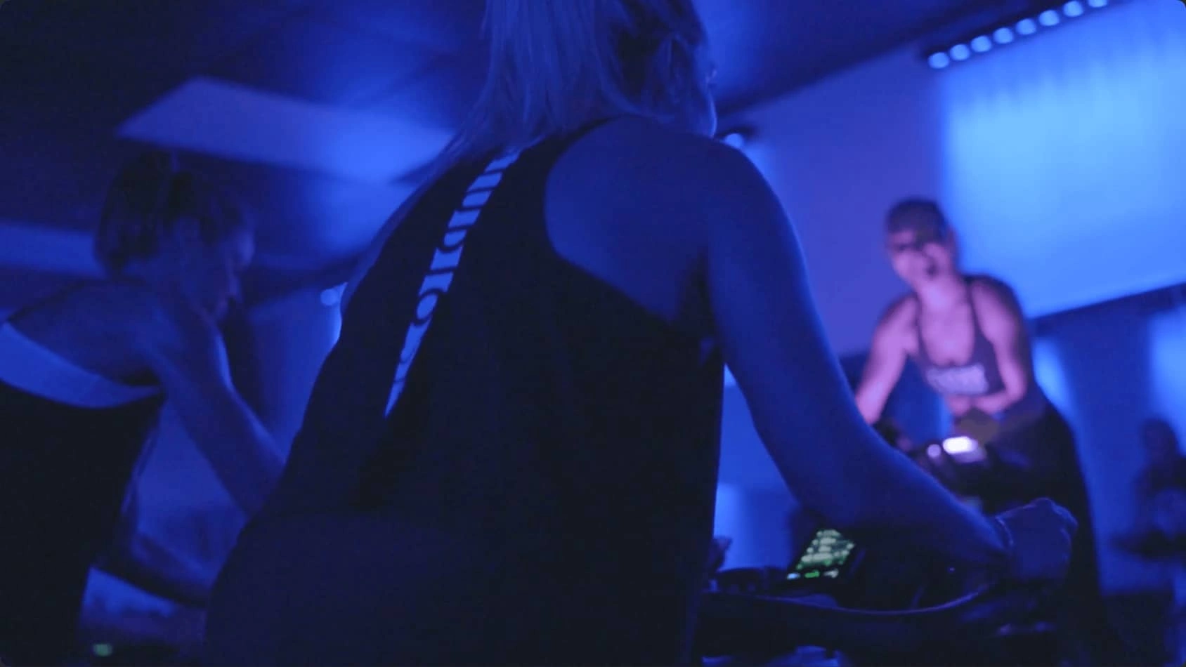 A Studio Spin rider cycling under blue studio lights.